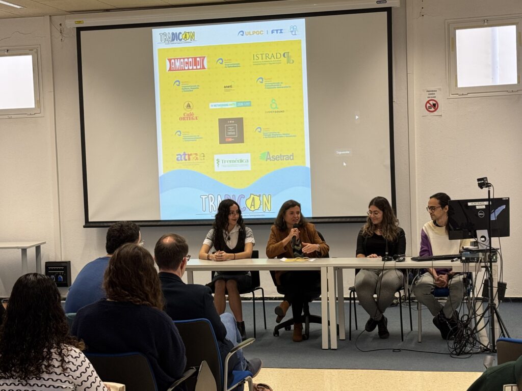 Mesa redonda de TRADICAN en la ULPGC con varias ponentes sentadas frente al público y una pantalla al fondo.